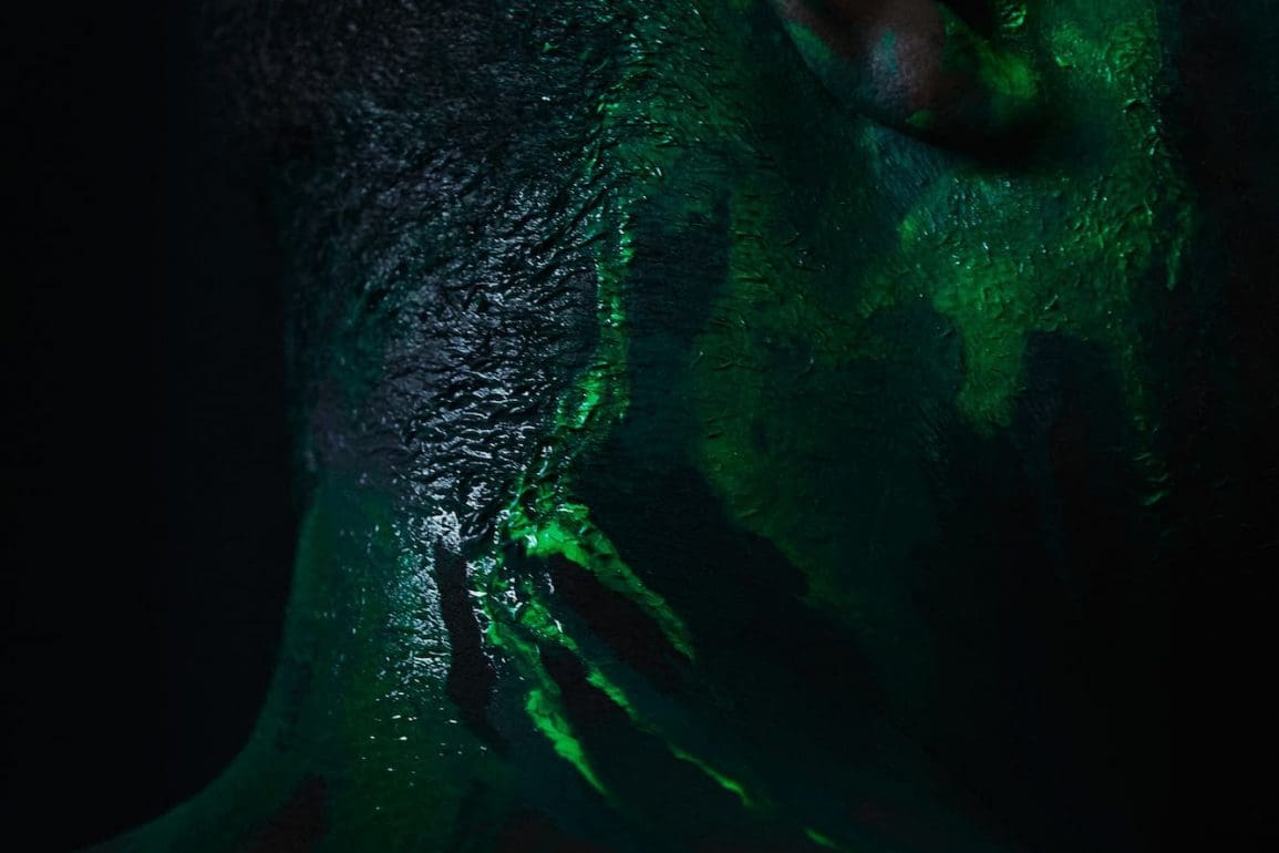 Neon green paint on a Black mans profile to depict an algal bloom