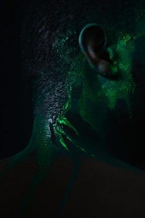 Neon green paint on a Black mans profile to depict an algal bloom