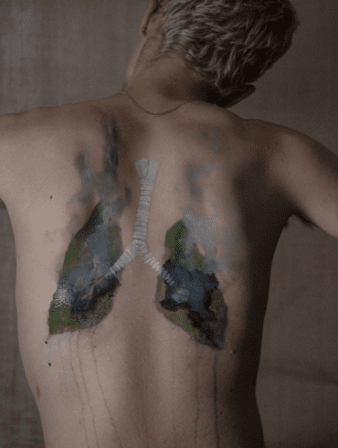 Burning lungs painted onto the back of a white man depicting land systems change.
