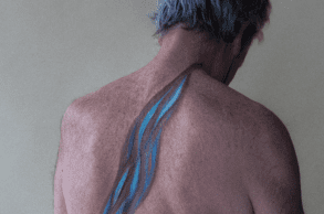 A photograph of an elderly white man with abstract elements of water painted down his back.