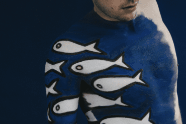 A man is painted with blue paint and white fish across his body